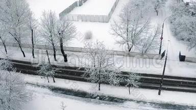 在城市里下雪，从一座高楼上射出，树木、灯笼和一个覆盖着雪的白色栅栏